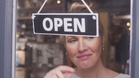 Inhaberin-Eines-Kleinunternehmens-Dreht-Sich-Um,-Schild-„Geöffnet“-Im-Geschäft-Oder-Café