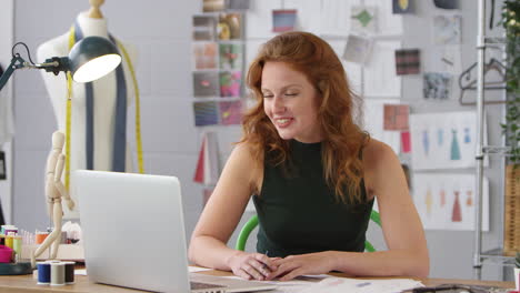 Female-Business-Owner-Working-In-Fashion-Showing-Designs-On-Video-Call-Using-Laptop