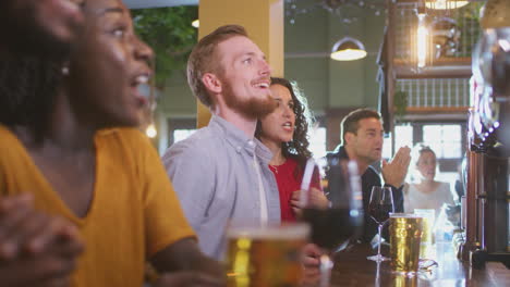 Group-Of-Excited-Customers-In-Sports-Bar-Watching-Sporting-Event-On-Television