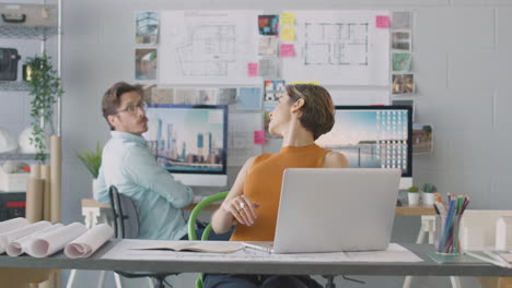 Male-And-Female-Architects-In-Office-Working-At-Desks-On-Computers-Joining-Up-For-Meeting-Together