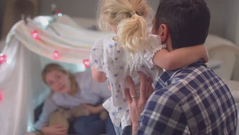 Laughing-parents-with-young-daughter-having-fun-in-homemade-camp-in-child's-bedroom-at-home---shot-on-slow-motion