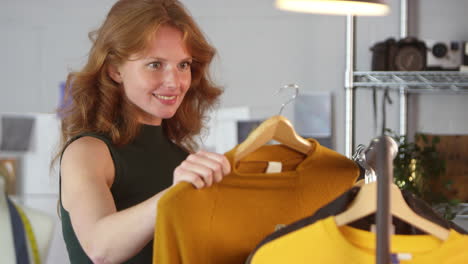Female-Clothes-Designer-Checking-Clothing-Samples-On-Rail-In-Fashion-Studio