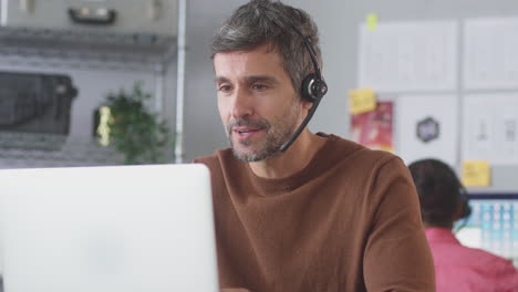 Businessman-Wearing-Telephone-Headset-Talking-To-Client-In-Customer-Services-Call-Centre