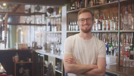 Portrait-Of-Smiling-Male-Bar-Worker-Standing-Behind-Counter