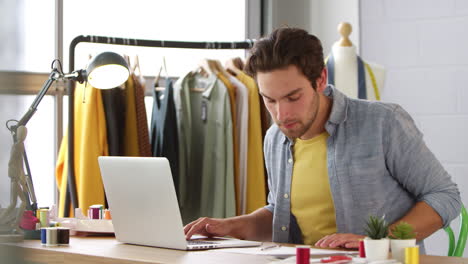 Male-Student-Or-Business-Owner-Working-In-Fashion-Using-Laptop-In-Studio