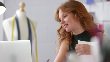 Female-Business-Owner-Working-In-Fashion-Showing-Designs-On-Video-Call-Using-Laptop