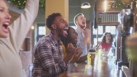 Group-Of-Excited-Customers-In-Sports-Bar-Watching-Sporting-Event-On-Television