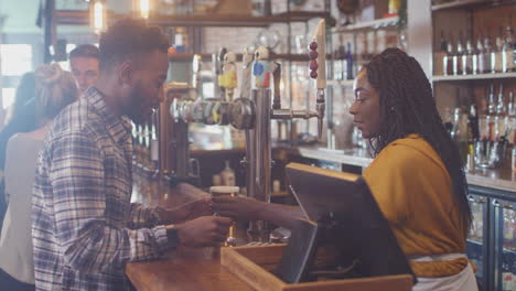 Male-Customer-In-Bar-Makes-Socially-Distanced-Contactless-Payment-For-Drinks-In-Health-Pandemic