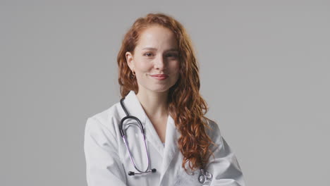 Studio-Portrait-Of-Smiling-Female-Doctor-With-Stethoscope-In-White-Coat-Against-Plain-Background