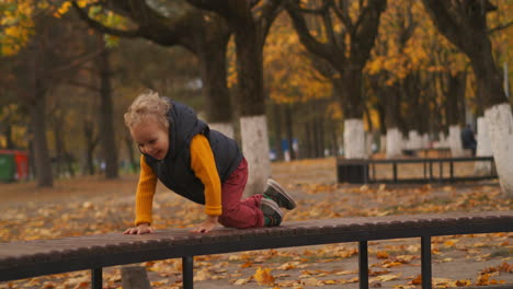 happy-little-boy-is-crawling-on-bench-in-city-park-walking-at-autumn-weekend-smiling-child-is-enjoying-carefree-childhood-naughty-and-cute-toddler