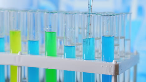 Lab-assistant-adding-green-liquid-in-test-tube-monitoring-chemical-reaction.-Technician-carefully-drips-the-solution-from-the-pipette-into-glass-tubes-for-DNA-analysis.-Pharmaceutics-Laboratory.-High-quality-4k-footage