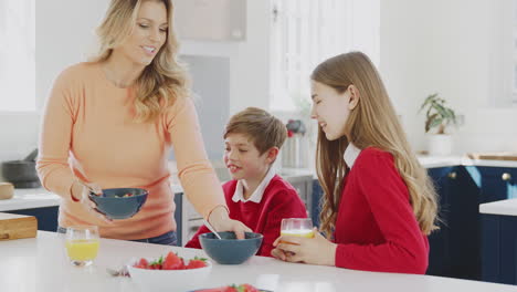 Mother-Having-Breakfast-With-Children-In-School-Uniform-At-Kitchen-Counter
