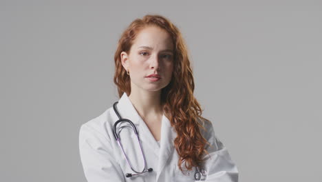 Studio-Portrait-Of-Serious-Female-Doctor-With-Stethoscope-In-White-Coat-Against-Plain-Background