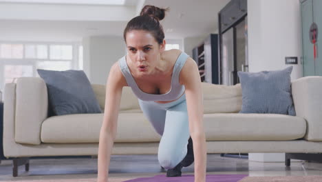 Woman-in-fitness-clothing-at-home-in-lounge-doing-stretches-and-exercising-with-hand-weights---shot-in-slow-motion