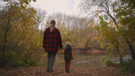 secret-lake-in-forest-mother-and-little-son-are-walking-on-shore-at-autumn-day-good-memories-about-childhood-happy-parenthood