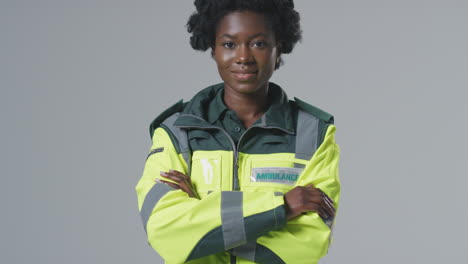 Full-Length-Studio-Portrait-Of-Smiling-Young-Female-Paramedic-In-Uniform-Against-Plain-Background