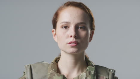 Retrato-De-Estudio-De-Una-Joven-Soldado-Seria-Con-Uniforme-Militar-Sobre-Fondo-Liso