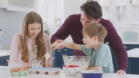 Father-With-Two-Children-In-Kitchen-At-Home-Having-Fun-Baking-Cakes-Together
