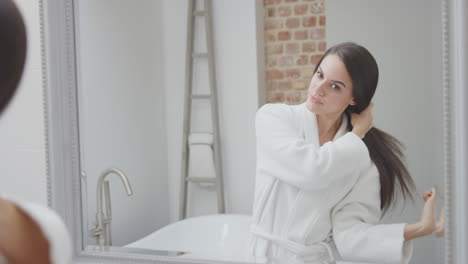 Couple-Wearing-Bathrobe-And-Pyjamas-Getting-Ready-In-Bathroom-Mirror-At-Home