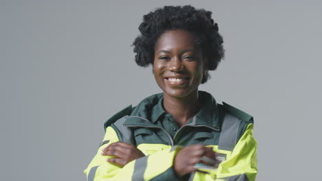 Studio-Portrait-Of-Smiling-Young-Female-Paramedic-In-Uniform-Against-Plain-Background