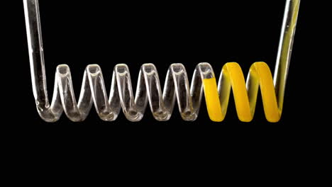 Die-Gelbe-Flüssigkeit-Füllt-Die-Glasspirale-Auf-Schwarzem-Hintergrund-In-Zeitlupe.-Chemischer-Kondensator-Auf-Schwarzem-Hintergrund.-Hochwertiges-4K-Filmmaterial