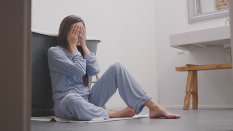 Enttäuschte-Frau-Sitzt-Zu-Hause-Auf-Dem-Badezimmerboden-Und-Hat-Einen-Negativen-Schwangerschaftstest