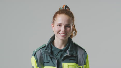 Studio-Portrait-Of-Smiling-Young-Female-Paramedic-Against-Plain-Background