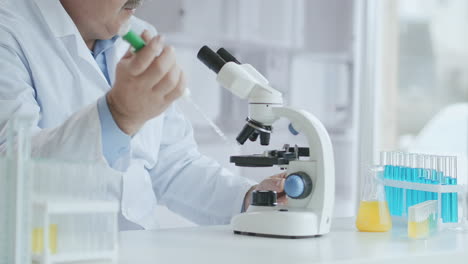 Bearded-Caucasian-male-researcher-wearing-protective-glasses-and-working-with-a-microscope-spbas.-scientist-using-microscope-in-a-laboratory.-Search-for-coronavirus-vaccine.-High-quality-4k-footage