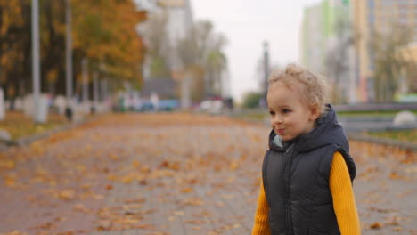 children-in-city-park-at-autumn-day-little-curly-boy-is-running-over-path-covered-dry-yellow-leaves-happy-weekend-and-resting-outdoors
