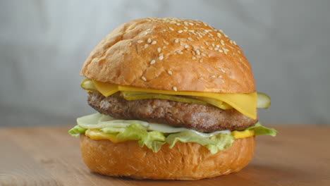 Yummy-fast-food-concept.-Fresh-homemade-grilled-burger-with-meat-patty-tomatoes-cucumber-lettuce-onion-and-sesame-seeds.-Unhealthy-lifestyle.-Food-background.