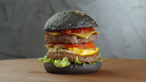 Burger-or-hamburger-with-black-bread-on-a-blurred-background-of-leaves