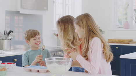 Children-Putting-Cake-Mixture-On-Mother's-Nose-In-Kitchen-As-They-Have-Fun-Baking-Cakes-Together