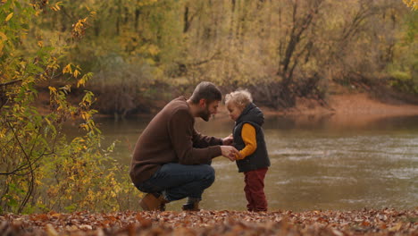 loving-father-and-little-son-are-communicating-at-nature-on-shore-of-lake-at-autumn-day-man-and-boy-are-snuggling-by-foreheads-touching-moment-and-joyful-memories