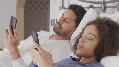 Paar-Im-Bett-Im-Schlafanzug,-Süchtig-Danach,-Mobiltelefone-Zu-Benutzen,-Im-Bett-Liegend-Und-Nicht-Kommunizierend