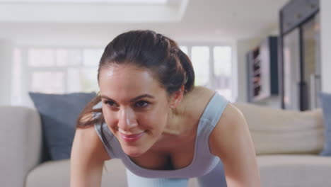 Woman-in-fitness-clothing-at-home-in-lounge-doing-stretches-and-exercising-on-mat---shot-in-slow-motion