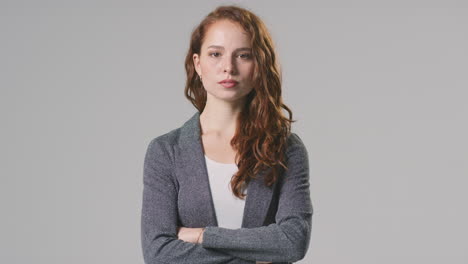 Studio-Portrait-Of-Serious-Young-Businesswoman-With-Folded-Arms-Against-Plain-Background