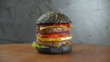 Black-Burger.-Ein-Burger-Mit-Schwarzen-Brötchen,-Saftigen-Marmor-Rindfleischscheiben,-Käse,-Frischem-Salat-Und-Barbecuesauce.