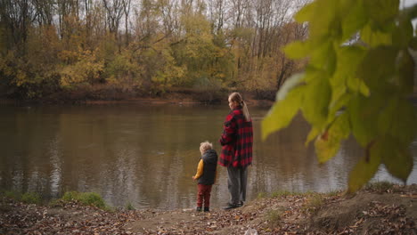 calm-weekend-at-nature-woman-and-her-little-son-are-admiring-forest-lake-at-autumn-day-walking-and-resting-in-woodland-or-park-area-happy-mother-and-child