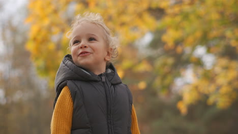 Porträt-Eines-Kindes-In-Der-Natur-Am-Herbsttag-Gegen-Vergilbte-Bäume-Am-Wochenende-Spaziergang-Im-Park-Mittlere-Aufnahme-Eines-Glücklichen-Kleinen-Jungen