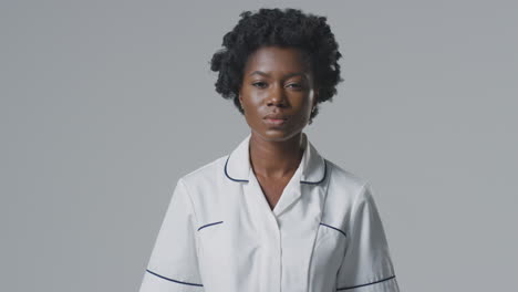 Studio-Portrait-Of-Serious-Female-Nurse-In-Uniform-Against-Plain-Background
