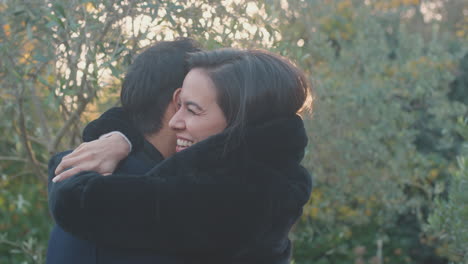 Loving-Young-Couple-Meeting-And-Hugging-Outdoors-In-Fall-Or-Winter-Countryside-Against-Flaring-Sun