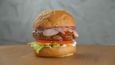 Toller-Burger-Mit-Rinderkotelett,-Tomaten,-Pilzen-Und-Gurken-Mit-Geschmolzenem-Käse-Dreht-Sich-Auf-Einem-Holzbrett-Auf-Hellem-Hintergrund.