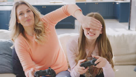 Mother-Cheating-As-She-And-Daughter-Have-Fun-Sitting-On-Sofa-At-Home-Playing-On-Games-Console