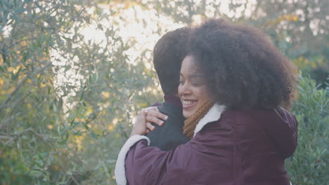 Loving-Young-Couple-Meeting-And-Hugging-Outdoors-In-Fall-Or-Winter-Countryside-Against-Flaring-Sun