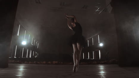 Slow-motion:-prima-ballet-in-a-black-dress-performs-rotations-and-dance-graceful-movements-rehearsing-a-solo-program.-The-camera-moves-on-gimbal.