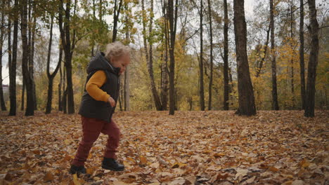 caucasian-light-haired-child-is-running-in-forest-at-autumn-day-having-fun-and-touching-tree-happy-childhood