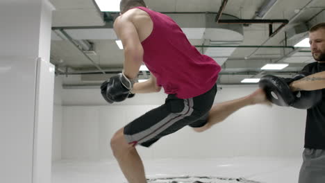 Coach-and-kick-boxers-practice-kicks-in-the-jump-with-rotation-on-the-paws-in-slow-motion.