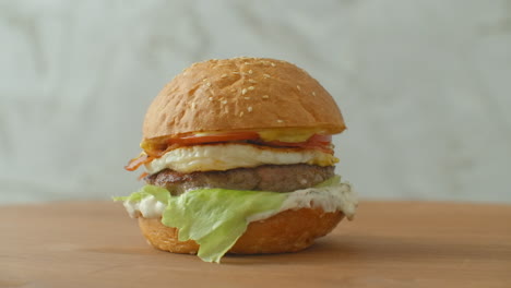 Yummy-fast-food-concept.-Fresh-homemade-grilled-burger-with-meat-patty-tomatoes-cucumber-lettuce-onion-and-sesame-seeds.-Unhealthy-lifestyle.-Food-background.