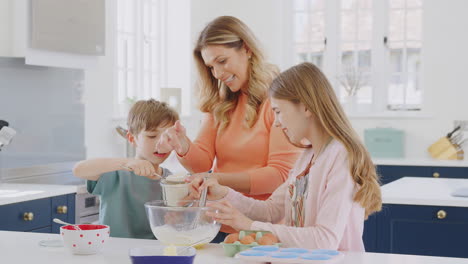 Mother-With-Two-Children-In-Kitchen-At-Home-Having-Fun-Baking-Cakes-Together