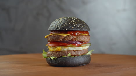 Burger-or-hamburger-with-black-bread-on-a-blurred-background-of-leaves